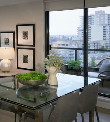 a living and dining area with a glass table and chairs and a view of the city