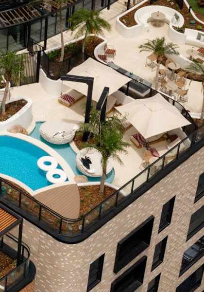 A rooftop pool area with a slide and lounging areas.