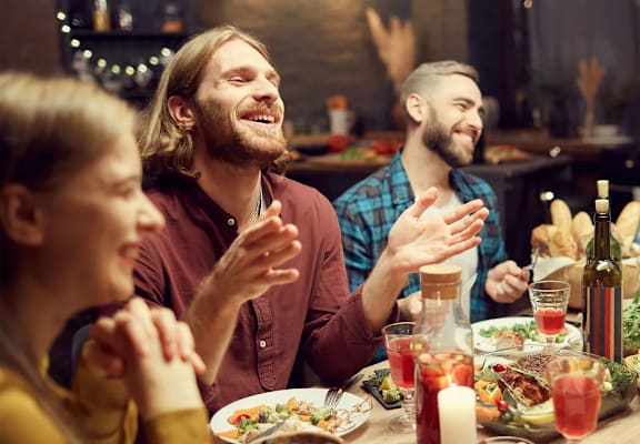 a group of people sitting around a dinner table talking and laughing