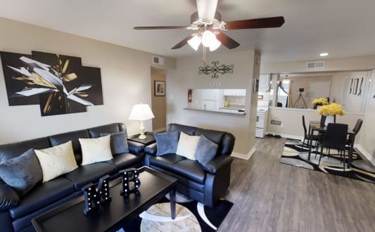 a living room with couches a coffee table and a ceiling fan