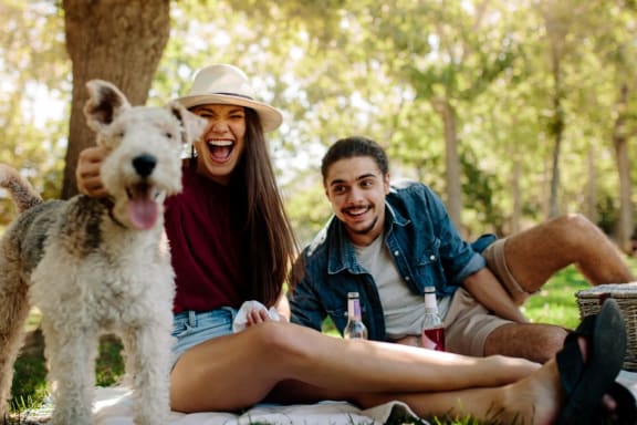 a group of friends sitting in the park with a dog