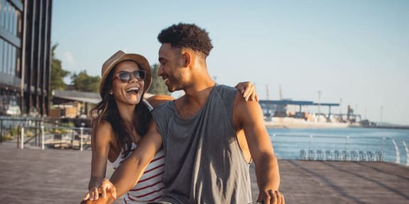 a man and a woman riding a bike on a boardwalk