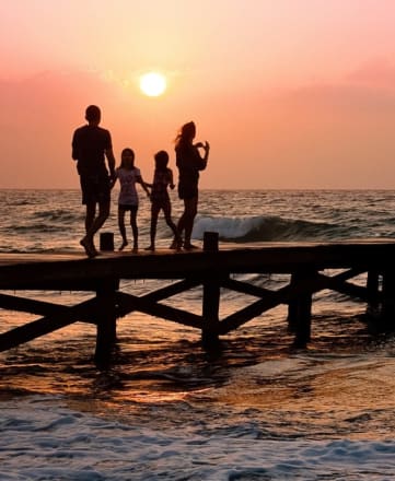a family walks along a pier at sunset