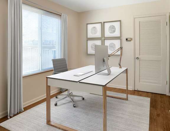 A white desk with a laptop and a phone on it in a room.