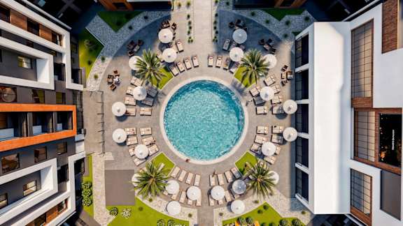 A pool surrounded by palm trees and lounge chairs.