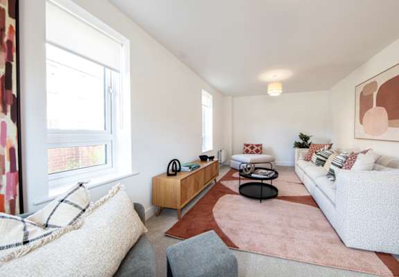 A living room with a grey couch, a white couch, a brown rug, and a painting on the wall.