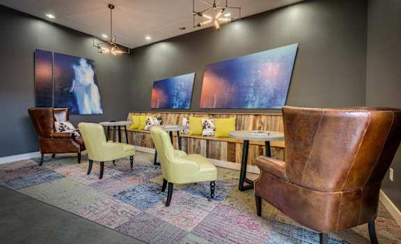 a room with a long table with yellow chairs and blue paintings on the wall