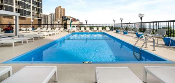 a swimming pool on the rooftop of a building with a city in the background