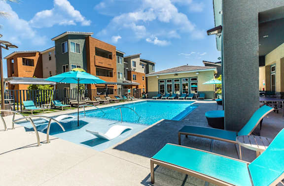 A swimming pool surrounded by lounge chairs and umbrellas at THE SOLANA APARTMENT HOMES, Las Vegas