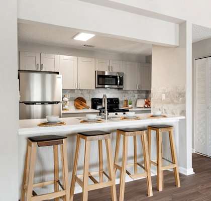 a kitchen with a bar and stools in front of a counter with a sink