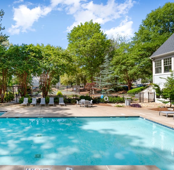 a pool with lounge chairs and a house in the background