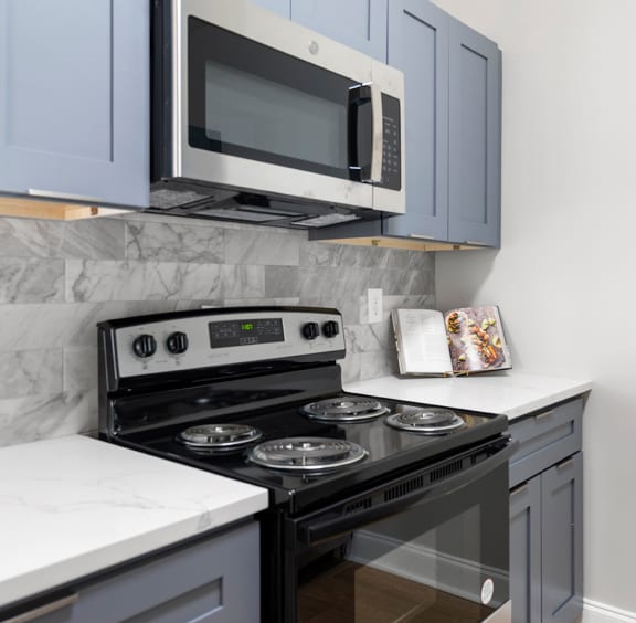 a kitchen with white cabinets and gray appliances