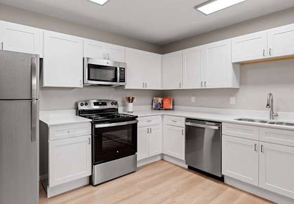an empty kitchen with white cabinets and stainless steel appliances
