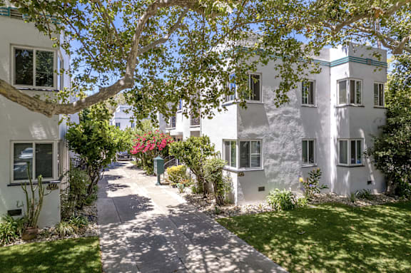 a sidewalk in front of some white buildings and trees