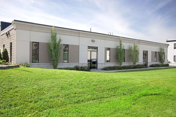 A building with a grey facade and greenery in front.