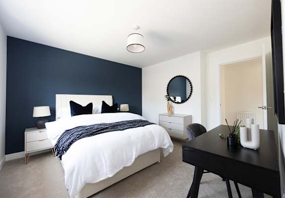 A bedroom with a white bed and a black table.