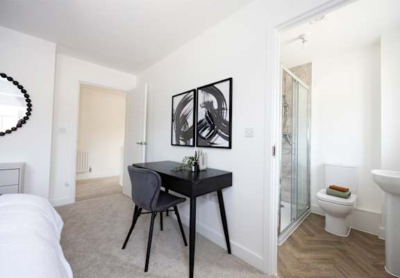 A black and white photo is hanging on a white wall above a black desk.