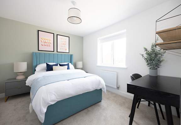 A bedroom with a bed, desk, and chair.
