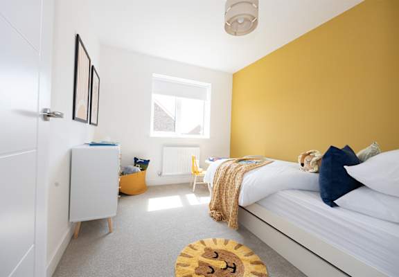A bedroom with a bed, a chair, a cabinet, and a window.