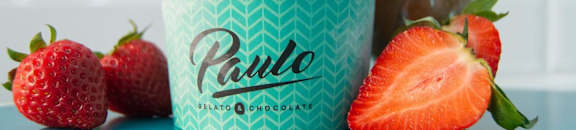 A cup of Paulo Bilato Chocolate ice cream with strawberries on the side.