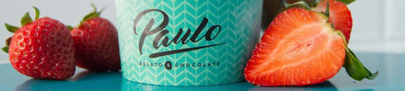 A cup of Paulo Bilato Chocolate ice cream with strawberries on the side.