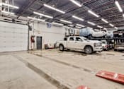 Thumbnail 2 of 5 - A white truck is parked in a garage with a red mat on the floor.
