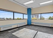 Thumbnail 3 of 13 - A room with a blue column in the middle and a large window with a view of the city.