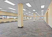 Thumbnail 11 of 13 - A large, empty room with carpeted floors and columns.
