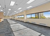 Thumbnail 12 of 13 - A long hallway with carpeted floors and windows on one side.