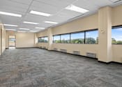 Thumbnail 13 of 13 - A large, empty office space with carpeted floors and large windows.