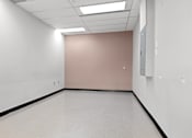 Thumbnail 5 of 13 - A room with white walls and a pink wall with a door.