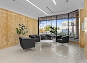 Thumbnail 4 of 13 - A modern office waiting area with black chairs and a wooden wall.