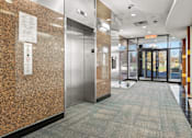 Thumbnail 4 of 9 - A hallway with a metal elevator and a sign on the wall.