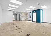 Thumbnail 3 of 5 - A room with a blue door and a stone wall in the background.