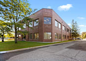 Thumbnail 2 of 6 - A red brick building with a parking lot in front.