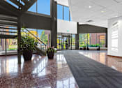 Thumbnail 3 of 6 - A hallway with a black carpet and a plant on the left side.