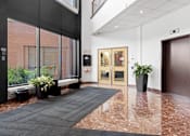 Thumbnail 4 of 6 - A hallway with a black carpet and a brown door.