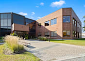 Thumbnail 1 of 6 - A modern building with a brick facade and large windows.