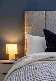 a bedroom with a bed and a nightstand with a lamp and a framed picture
