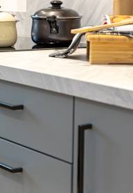 a modern kitchen with grey cabinets and black appliances