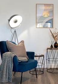 a dining room with a wooden table and blue chairs and a blue wall with artwork