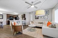 A living room hardwood-style flooring and a ceiling fan