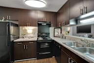 A modern kitchen with dark brown cabinets and black appliances.