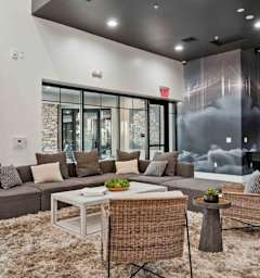 A modern living room with a grey sofa, a white coffee table, and a woven chair.