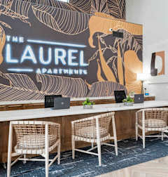 A conference room with a large table and chairs with a backdrop that says "The Laurel Apartments".