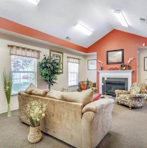 A living room with a beige couch, a chair, and a fireplace.