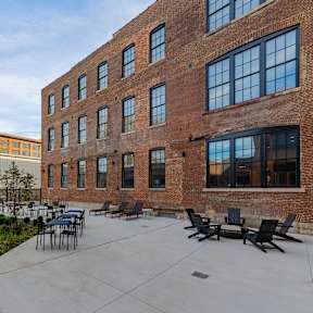 A courtyard with a table and chairs surrounded by brick buildings.