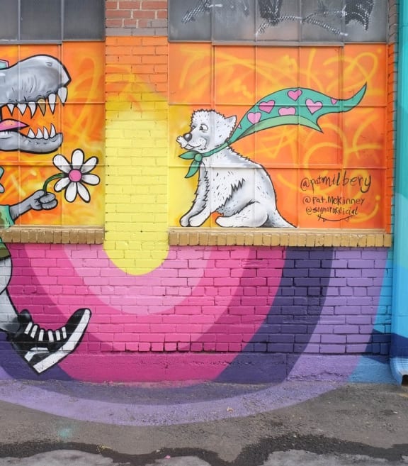 a mural on a wall of a person walking a dog and a shark