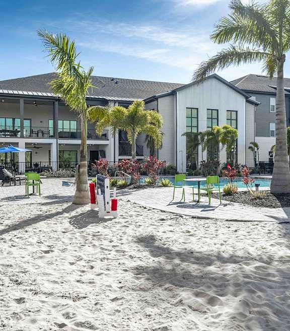 A sandy area in front of a building with palm trees.