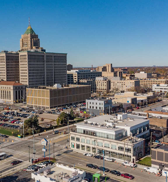 A cityscape with a large building featuring a green dome on the left and a busy intersection in the foreground.